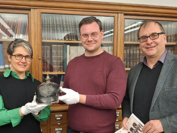 Übergabe der Pickelhaube am 16.12.2024 in der Bibliothek des Museums, v.l.n.r. Dr. Johanna Sänger, Eric Buchmann, Dr. Anselm Hartinger, Foto: Katja Etzold