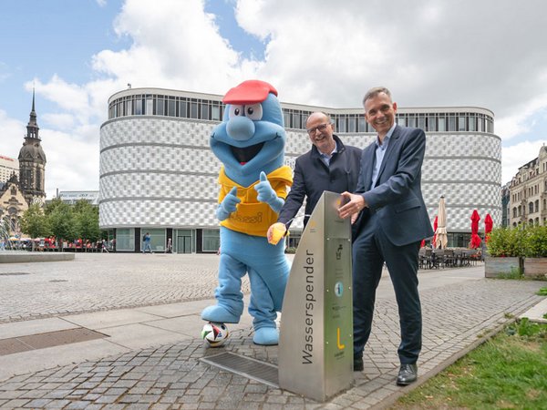 Wasser marsch in der Fanzone Richard-Wagner-Platz: Wasserwerke-Geschäftsführer Dr. Ulrich Meyer (r.) und Mario Hoff, Leiter des Kundenservices, nahmen mit Maskottchen Wassi den EM-Brunnen in Betrieb. Foto: Leipziger Gruppe