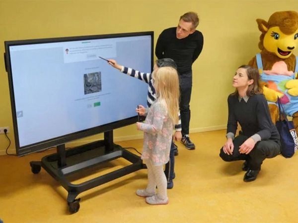 Emma und Daniel sind schon ziemlich fit im Umgang mit "ihrem" interaktiven Display. Kitaleiter Frank Simmank, Jugendbürgermeisterin Vicki Felthaus und das Kivan-Maskottchen (von links) schauen interessiert zu. Foto: Stadt Leipzig