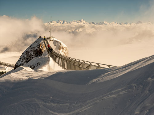 Das Gebiet Glacier 3000 mit der weltweit einzigen Hängebrücke zwischen zwei Berggipfeln. Menschen machen Fotos auf der Brücke. Berühmte Wahrzeichen. Foto: HeyingPhoto / depositphotos.com